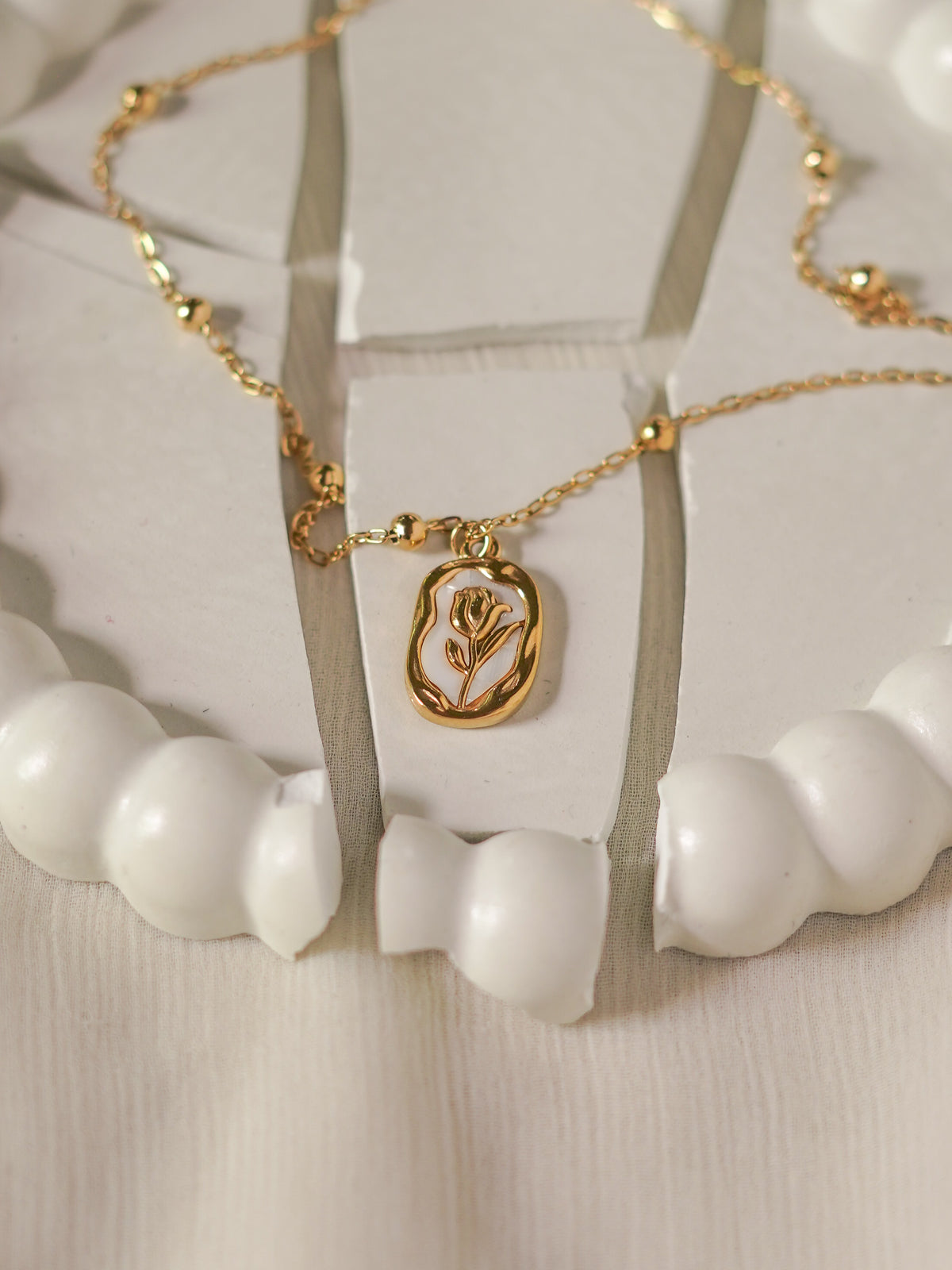 Gold necklace with a floral pendant on a white background