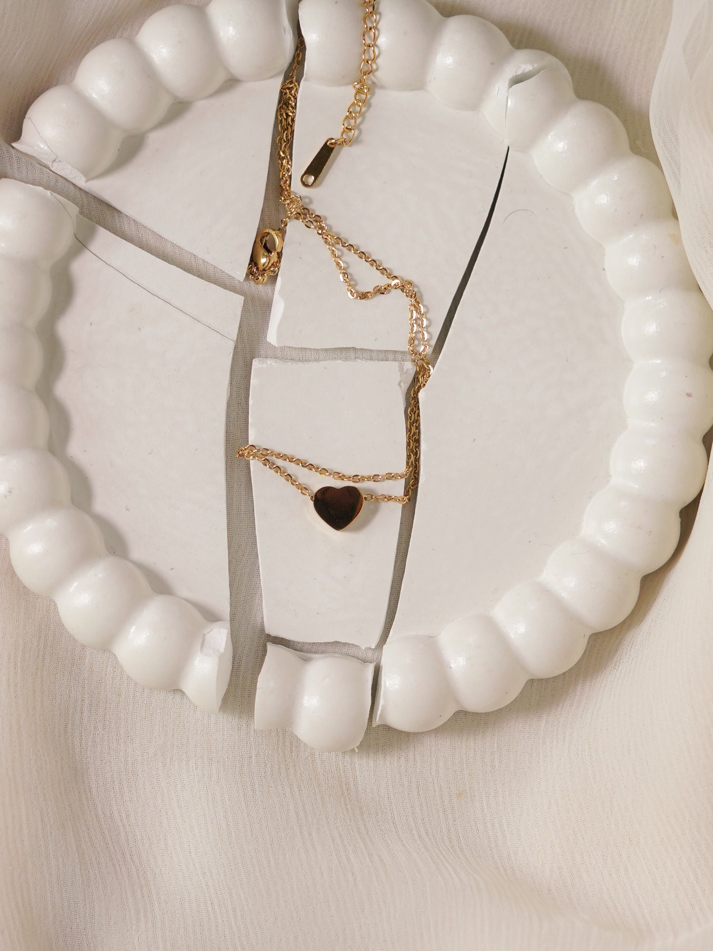 Gold necklaces with heart pendants on a white beaded necklace