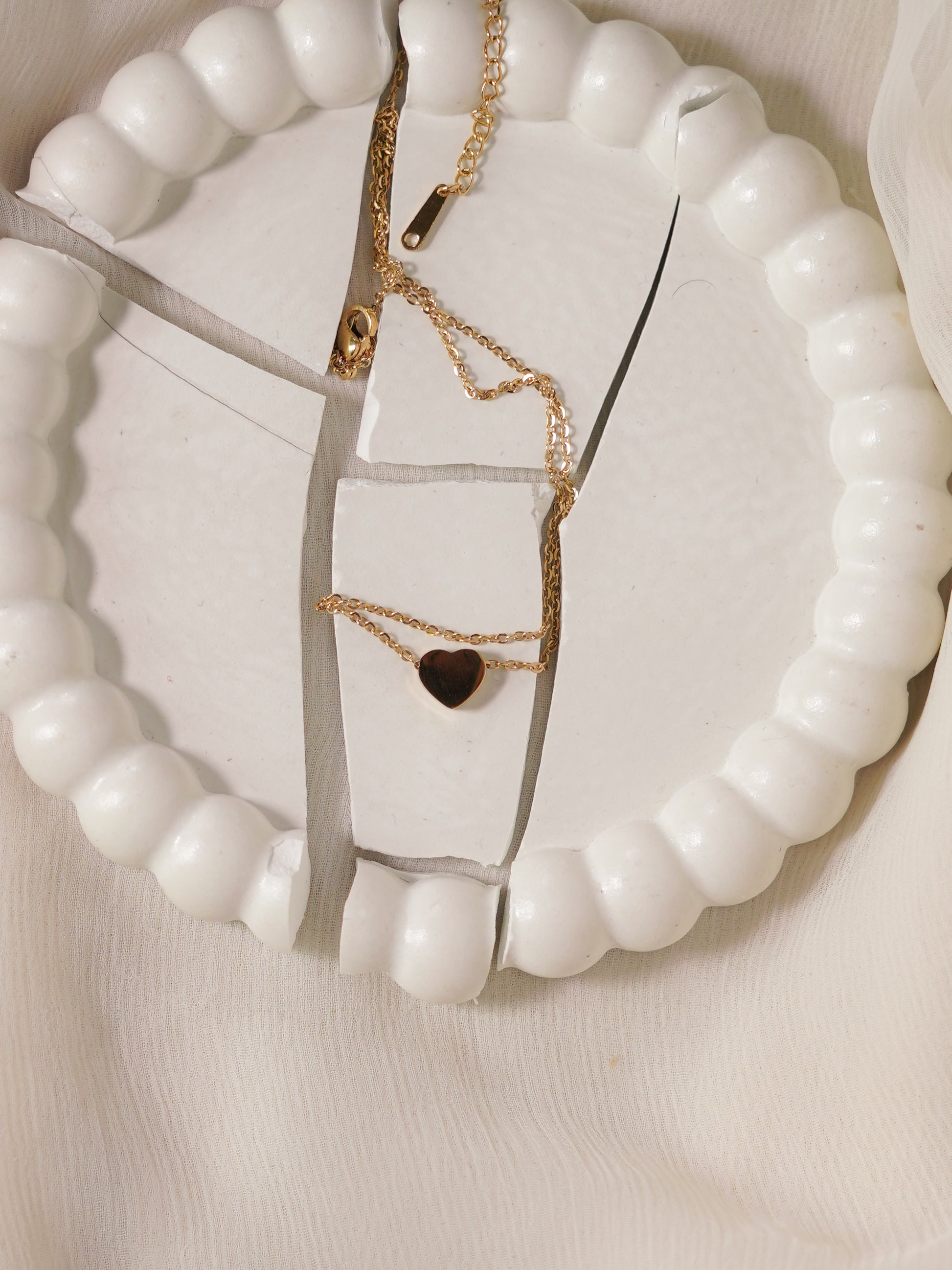 Gold necklaces with heart pendants on a white beaded necklace