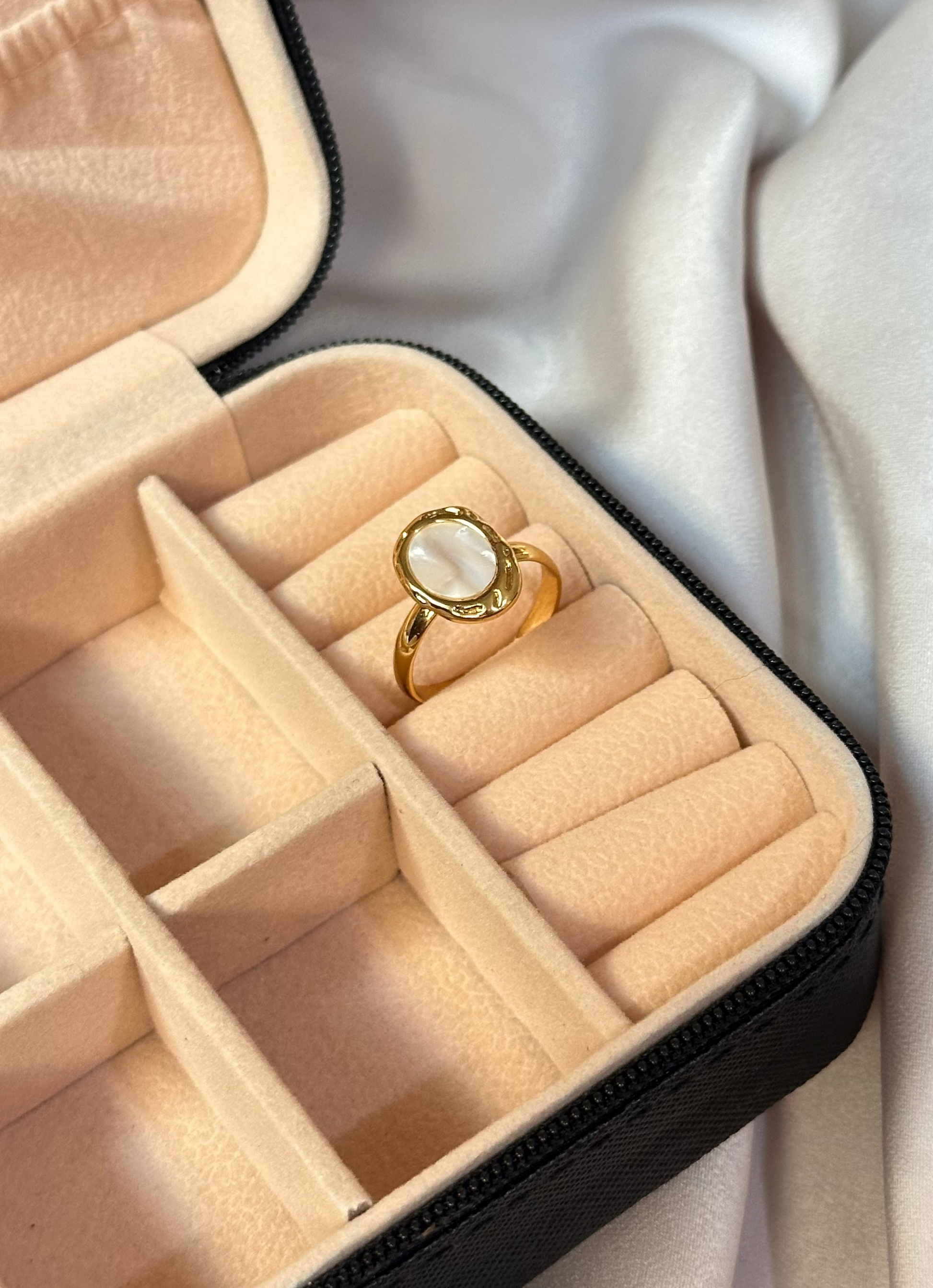 Jewelry box with a ring inside on a white fabric background
