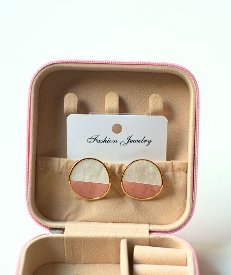 Round earrings in a pink jewelry box with a visible brand card.