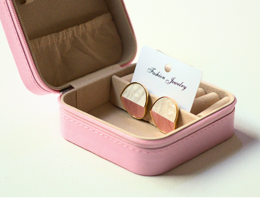 Pink jewelry box with gold earrings on a white background