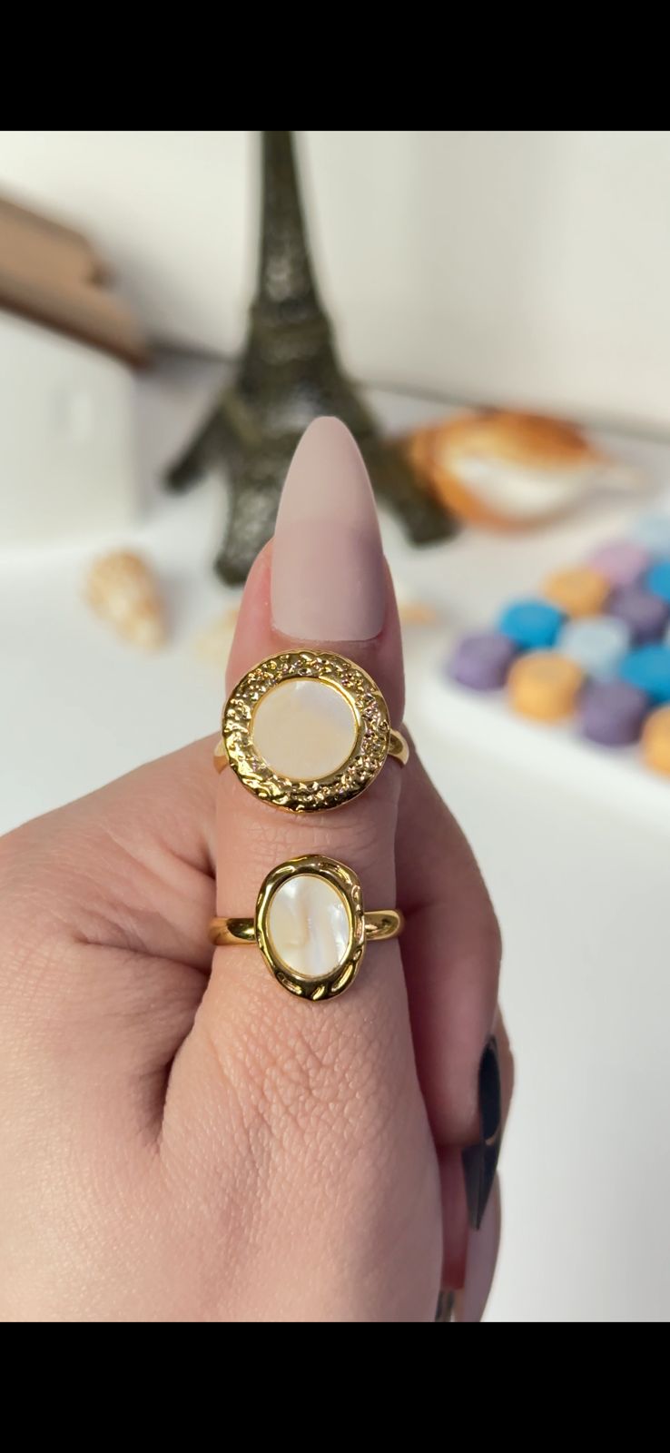 Gold ring with a central stone on a finger against a blurred background